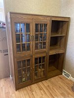 Full view of the brown cabinet with glass-paneled doors on the left side and open shelving with pull-out shelf on the right side.