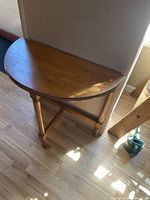 Half moon shaped wooden side table with smooth surface and warm finish, showing the top and front view.