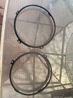 Two circular black Jeep headlight accessory rings placed on a glass table showing mounting tabs.