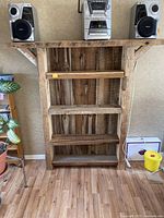 Front view of the reclaimed barn board wooden shelving unit with four shelves and items on top.