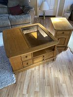 Photo showing a square oak coffee table and matching side table, both with glass tops and wooden drawers.