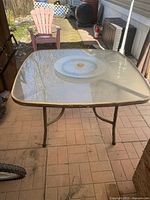 Full top view of square patio glass table showing the lazy Susan and umbrella hole in the center, outdoor setting.