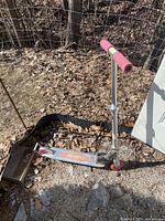 Side view of the silver Razor folding scooter showing pink foam handle grips, deck with logo, and metal rear brake.