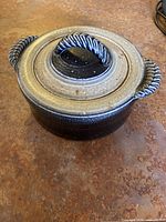 Casserole dish with lid on showing twisted blue and grey handles and overall ceramic glaze finish.