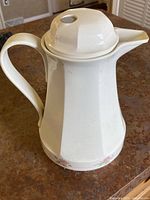 Full view of the white plastic carafe with handle, spout, and lid on top, showing overall shape and design.