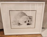 Framed sealed print showing the entire framed art. White wood frame, visible glass, matting, and seal image in black and white.