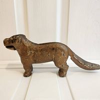 Side profile view of antique cast iron dog-shaped nutcracker showing wear on original paint and solid build.