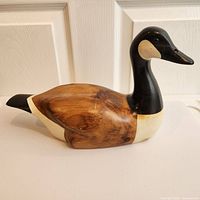 Side view of carved and hand-painted wood Canada goose showing body and head detail.