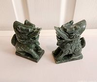 Front side view of both carved stone Foo dogs showing detailed facial features and circular body engravings