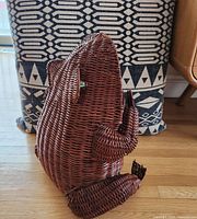 Side view of large wicker frog basket showing body, legs and green marble eyes.