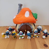 Front view of large Smurf house with nine Smurf figurines arranged in front showing details of the house and figures