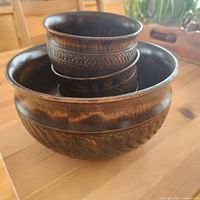 Top-down view showing one large wooden bowl holding three smaller bowls with carved decorative patterns on their outer sides.
