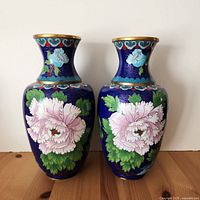 Front view of two matching cloisonne vases with pink flowers and gold rims.