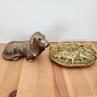 Front view of vintage brass dog figurine and brass ashtray on wooden surface
