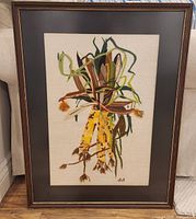 Full front view of the framed crewel embroidery showing the entire artwork, corn cobs and husks in varied earth tones on beige fabric, dark brown frame with gold trim.