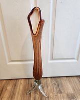 Front view of the tall amber-brown pulled glass vase standing on three clear glass feet, showing the narrow base widening upwards.