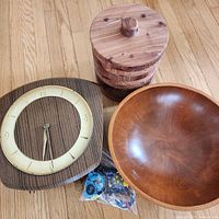 Photo showing vintage German wood clock, handmade segmented wood canister with lid, round wooden bowl, and assorted fridge magnets on wood floor.