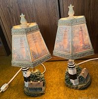 Pair of lighthouse themed hexagonal table lamps with multicolor lampshades and detailed resin bases featuring lighthouses and buildings.