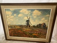 Full framed wall art showing landscape with windmill, tulip fields, houses, and clouds in textured print.