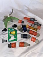 Wide view of various garden hose quick connect fittings and a green sprinkler base