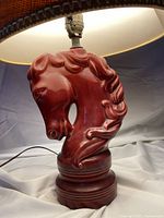 Close-up of the red ceramic horse head lamp base, showing detailed carving and glossy finish