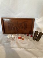 Image showing the wooden tray with engraved scenes and four sets of assorted salt and pepper shakers in front, highlighting the variety in styles and materials.