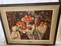 Framed print of Cezanne's "Apples and Oranges" featuring a still life of apples and oranges with linen mat and wood frame.
