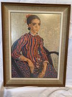 Framed print artwork showing a seated young woman in a red and blue dress, wooden frame visible with minor signs of wear.