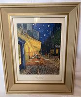 Frontal view of framed print showing the full artwork and frame, with "Outdoor Cafe" night scene