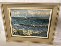 Front view of the framed print showing stormy sea with sailing boats and off-white wooden frame.