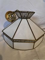 Side view showing the octagonal shape, white glass panels and brass metal framework with mounting plate attached.