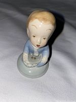 Front view of a small Wade Beggar Man ceramic figurine showing facial details, clothing, and basket held in hands.