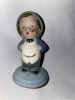 Front view of ceramic figurine showing detailed facial features, clothing, and base