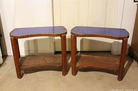 Pair of kidney-shaped Art Deco cocktail tables, showing cobalt blue mirrored tops and wooden frame with lower shelves
