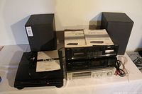 Full lot front view showing stacked stereo components with manuals and speaker pair at rear