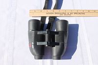 Top view of black Jason Perma Focus 2000 binoculars with central focusing mechanism and ribbed grips. A ruler measuring approximately 7 inches is placed above for size reference.