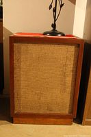 Front view of first speaker showing wood cabinet and fabric grille