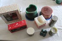 Multiple scented Christmas candles including two unopened Yankee Candle gift sets, assorted colored pillar candles, votives and jar candles.