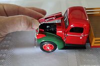 Close-up image showing the front and open hood of one red and green 1941 Chevy stake truck model displaying detailed engine compartment.