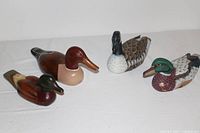 Four wood duck decoys arranged side by side, showing variation in coloration and style.