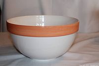 Vintage extra large ceramic serving bowl with white body and peach colored band near the rim