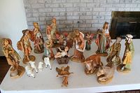 Wide shot of the nativity set showing all 15 figures and 10 animals arranged on a table in front of a brick wall and fireplace.