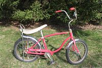 Side view of the entire red Schwinn Sting Ray bicycle showing banana seat, chrome fenders, chopper handlebars, and curved frame.