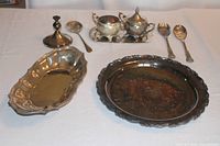 Photo showing entire silverplate tea service and serving pieces including sugar bowl, cream pitcher, tray, oval dish, serving piece, utensils, platter, and candle holder.