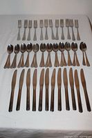 Full 48-piece flatware set arranged on a white surface showing forks, spoons, and knives.