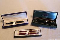 Overall lot with Waterman rollerball pen in blue box, Cross Solo Classic pen and pencil set in black box, and empty pen container for Cross set.