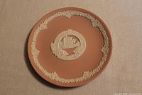 Pink Wedgwood decorative plate with white relief Bermuda Moongate image and floral border.