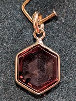 Close-up front view of hexagonal brownish lab diamond pendant with gold framing