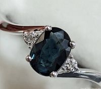 Close-up front view of the ring showing the oval sapphire center stone and diamond accents on white gold band.