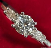 Close-up front view showing central round brilliant diamond and side marquise diamonds.